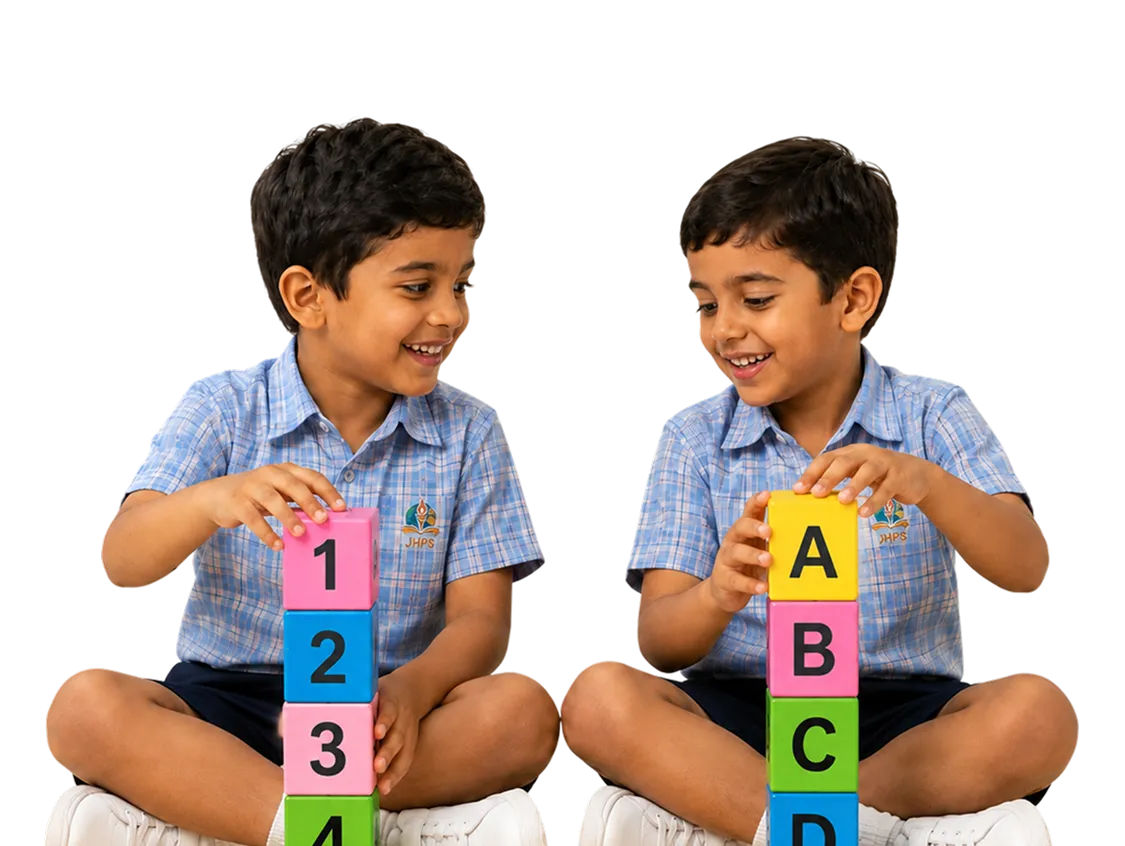 Two JHPS students smiling as they stack coloured number and letter blocks