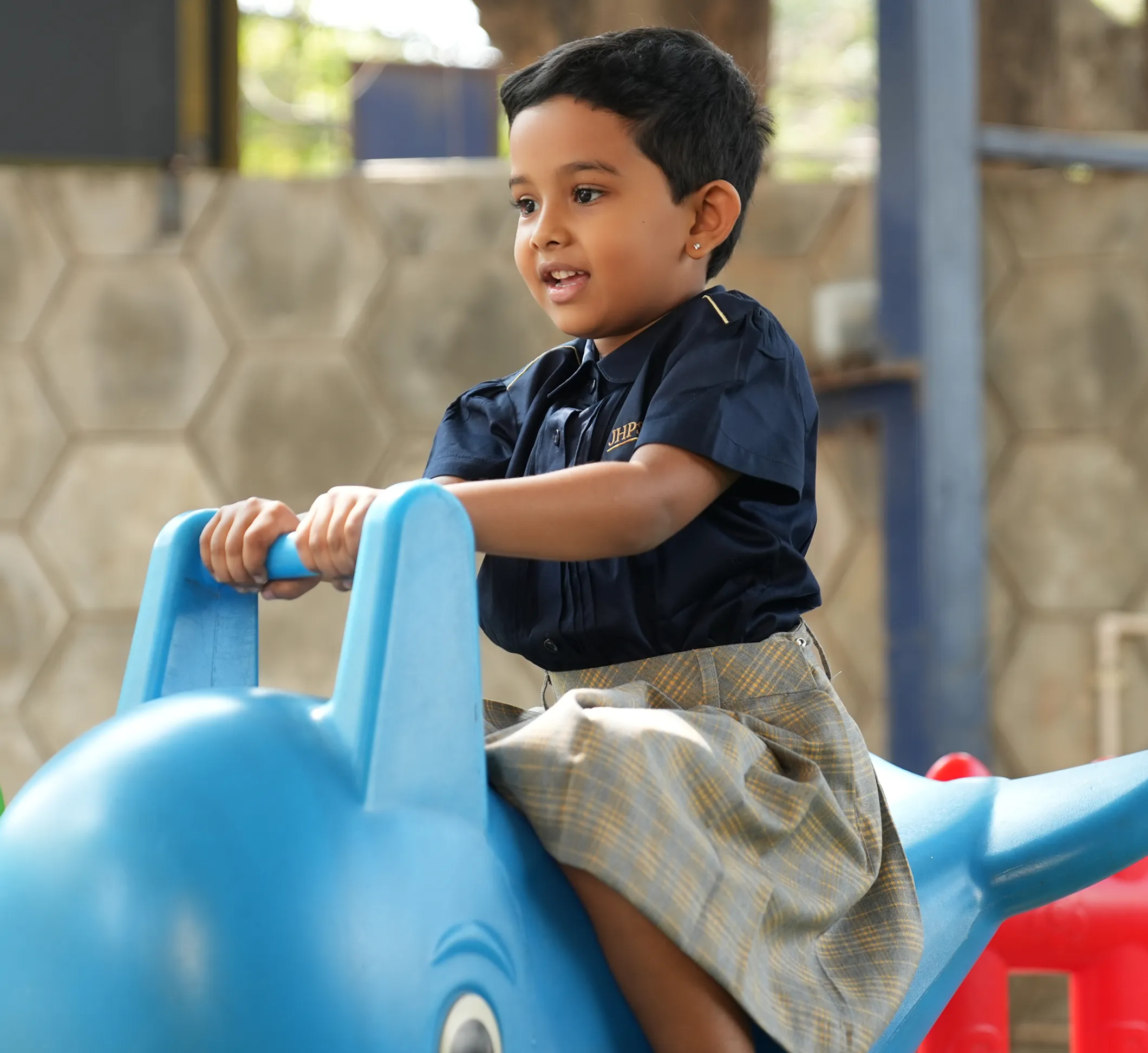 JHPS student riding a toy at the campus playground